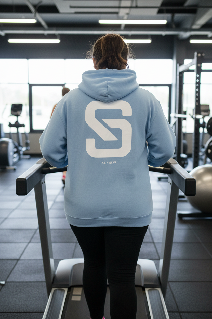 Person wearing a light blue hoodie with a large white logo in a gym setting
